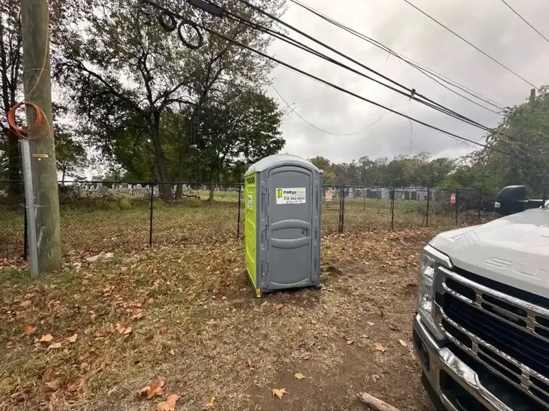 Single PottysPlus portable toilet in a pastoral outdoor field for seasonal or park use