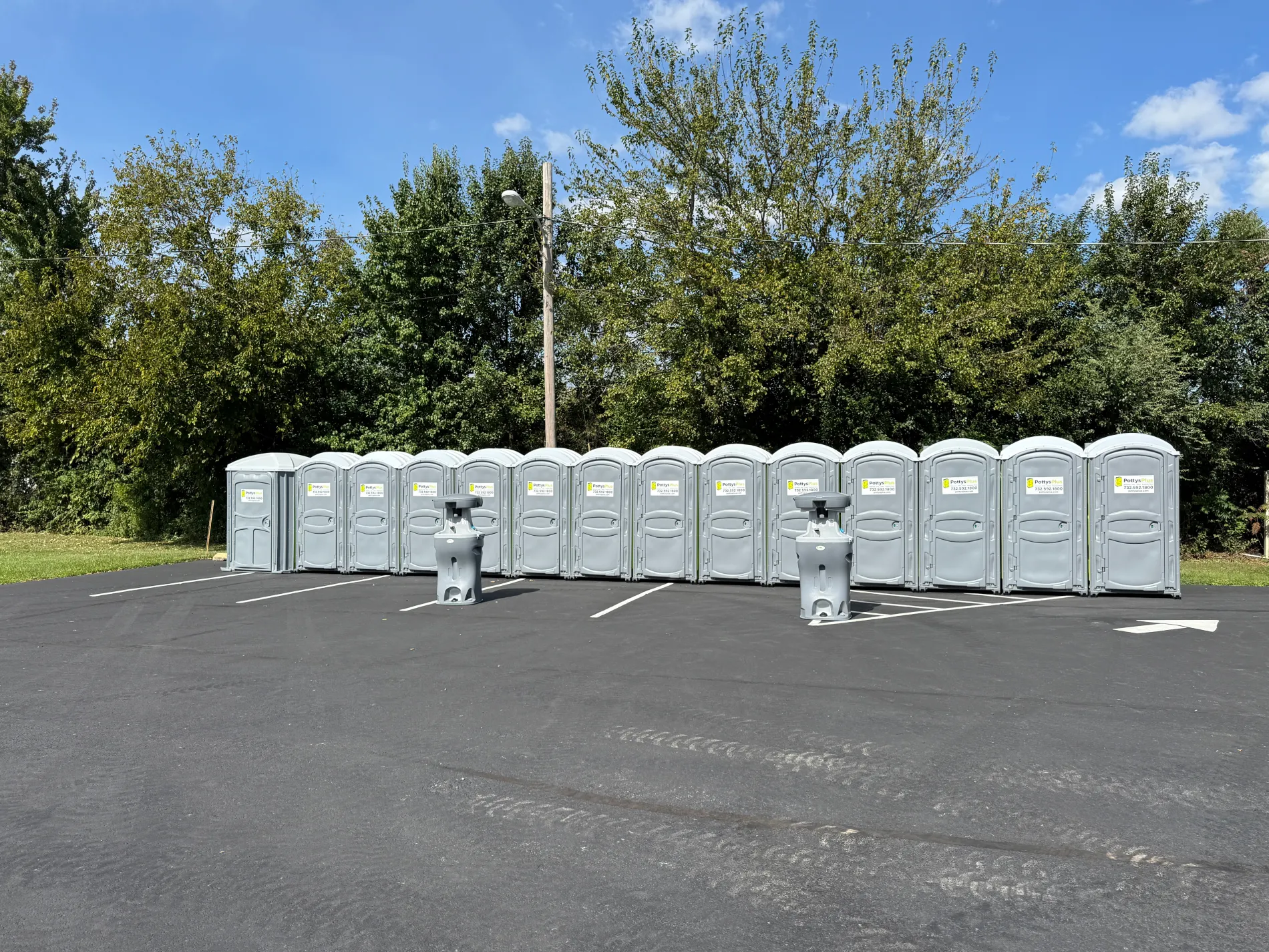 Portable toilet rentals lined up in a paved lot in New Jersey.