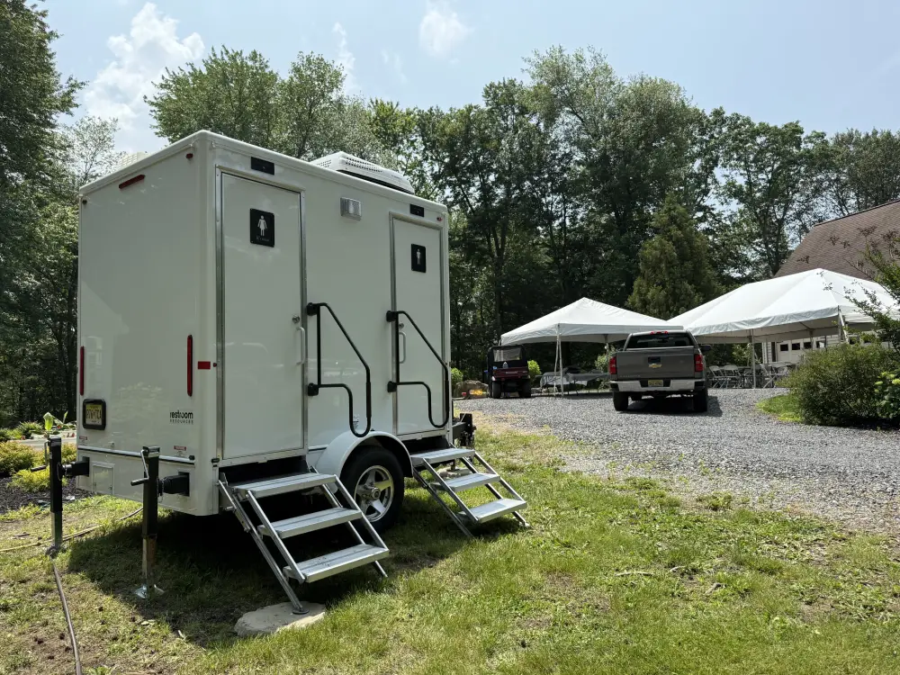 Portable restroom trailer positioned beside an event tent in New Jersey